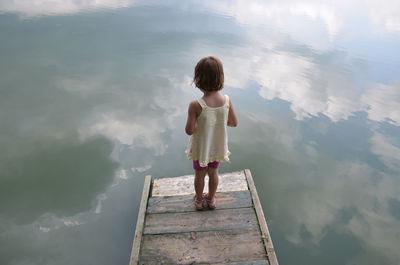 Rear view of woman standing on pier over water