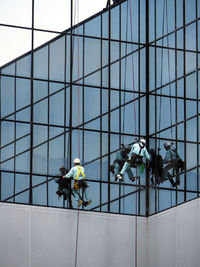 Low angle view of window washers working on modern building