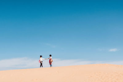 Friends standing in desert against sky