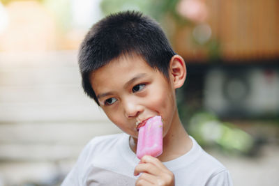 Boy looking away while eating popsicle