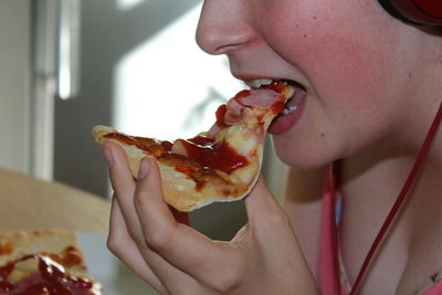 Midsection of young woman eating pizza