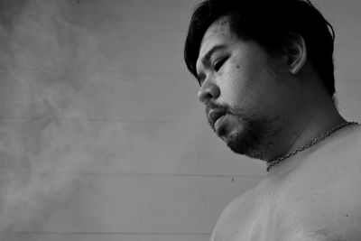 Portrait of young man looking away against wall