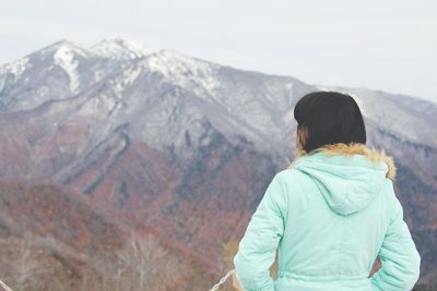 Rear view of woman looking at mountains against sky