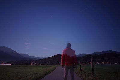 Rear view of man walking on footpath at night