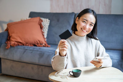 Young woman using mobile phone while sitting at home