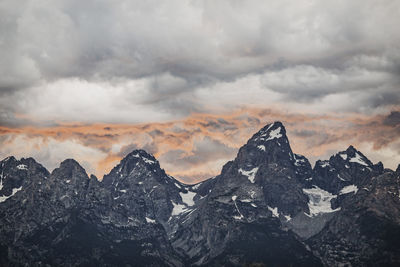 Setting sun reflects off clouds behind summits of the tetons, wyoming.