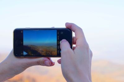 Midsection of person photographing through mobile phone