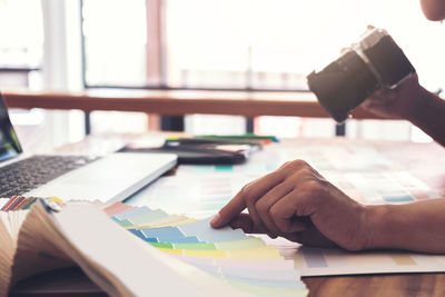 Cropped hand of man photographing color swatch at desk