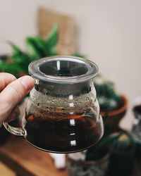 Close-up of hand holding glass jar on table