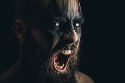 Portrait of a viking warrior with black war paint, screaming with rage and anger