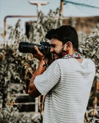 Side view of man photographing through camera