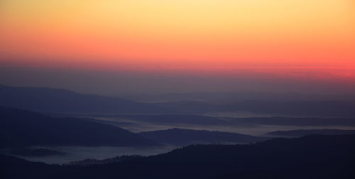 Scenic view of silhouette mountains against romantic sky at sunset