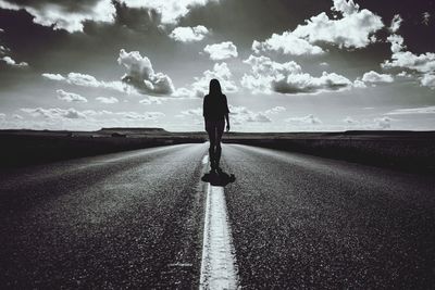 Rear view of woman standing on road against sky