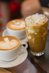 Close-up of two coffee cups and an iced coffee
