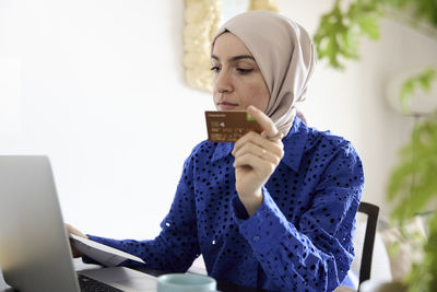 Woman in headscarf paying bills online at home