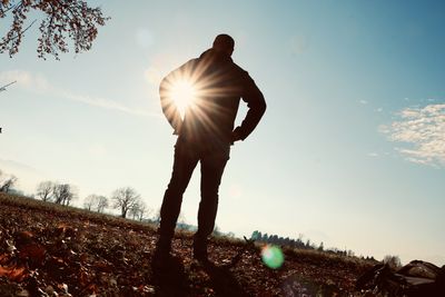 Man standing on field against sky on sunny day