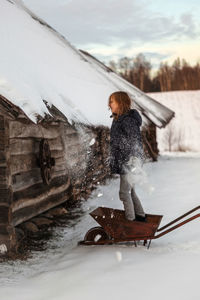 Full length of person on wheelbarrow against the winter snow