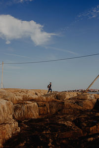People on rock formation against sky