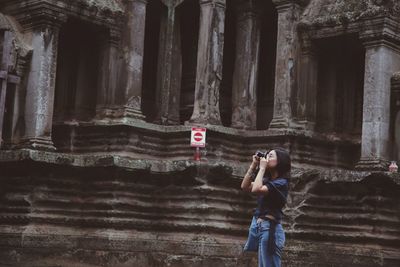 Woman photographing while standing against temple