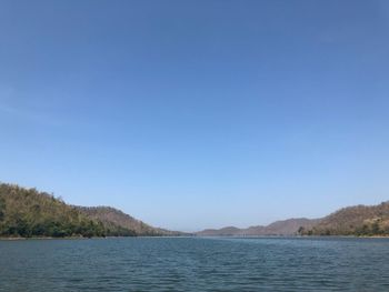 Scenic view of lake and mountains against clear blue sky