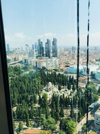 Panoramic view of buildings against sky seen through glass window