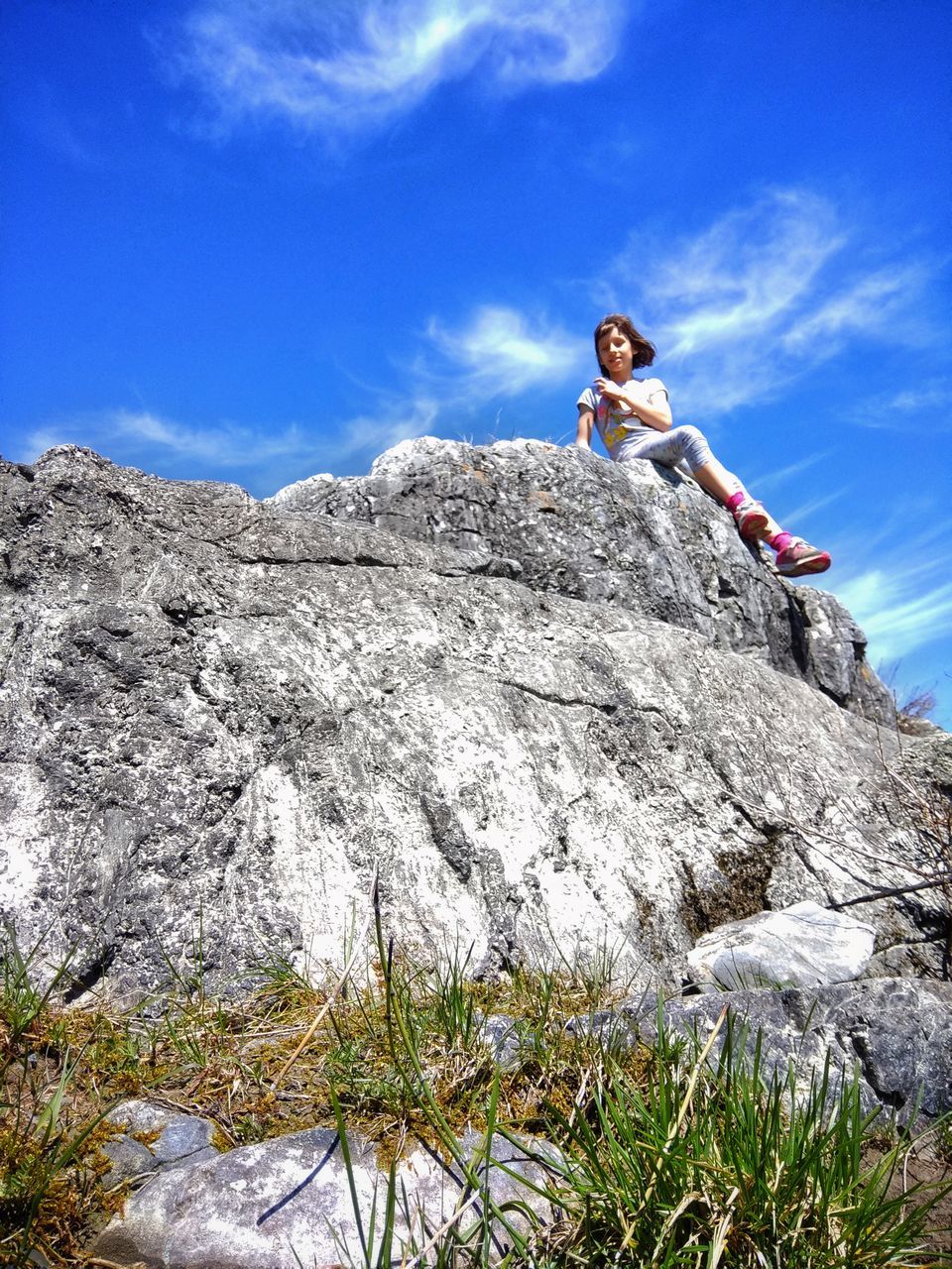 leisure activity, one person, low angle view, sky, rock, real people, solid, lifestyles, full length, casual clothing, rock - object, young adult, climbing, adventure, sport, nature, women, day, cloud - sky, outdoors