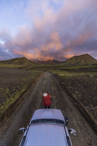 Photographer taking picture of sunset on mountains in front of car