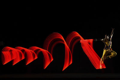 Low angle view of illuminated lighting equipment against black background