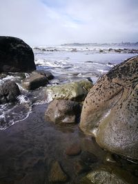 Close-up of sea waves splashing on beach against sky