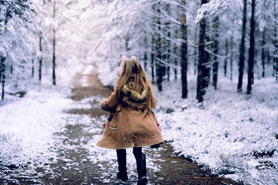 Rear view of woman walking on snow covered land