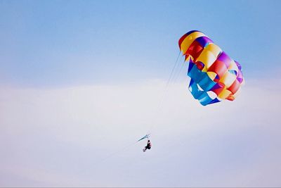 Low angle view of person parasailing against sky
