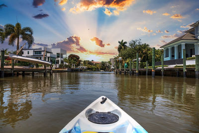 Scenic view of river by buildings against sky at sunset