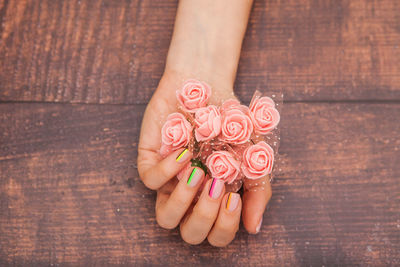 High angle view of woman hand holding pink rose