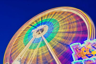 Low angle view of illuminated ferris wheel against blue sky