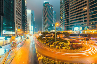 Light trails on city street amidst buildings at night
