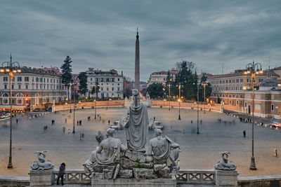 Statue in city against sky