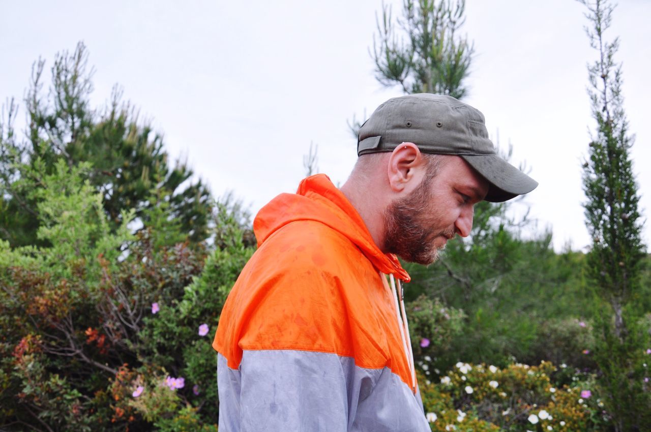 one person, plant, clothing, real people, men, side view, day, nature, mid adult men, mid adult, tree, orange color, lifestyles, adult, hat, males, looking, beard, outdoors, warm clothing