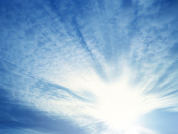 Low angle view of sunlight streaming through clouds