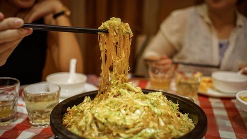 Midsection of friends having noodles in restaurant