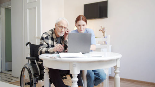 Nurse and senior man looking at laptop