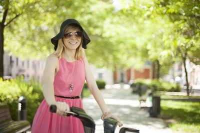 Woman in pink dress riding bicycle in park