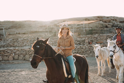 People riding horse in ranch against sky