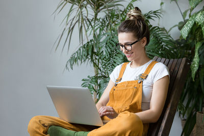 Smiling woman using laptop while sitting at home 