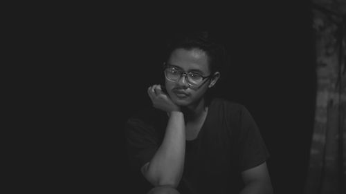 Portrait of young man wearing mask against black background