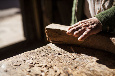 Fingerless hand of anonymous elderly woodworker over piece of wood in joinery