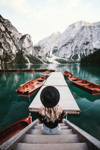 Rear view of woman sitting on staircase by lake