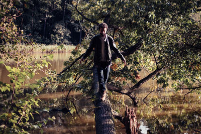 Man walking on fallen tree in lake