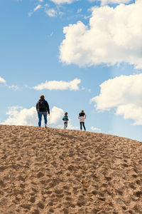 Rear view of people walking on sand