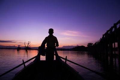 Silhouette man standing on lake against sky during sunset