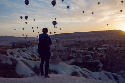 Man with backpack tourist standing on a rock at dawn with balloons cappadocia